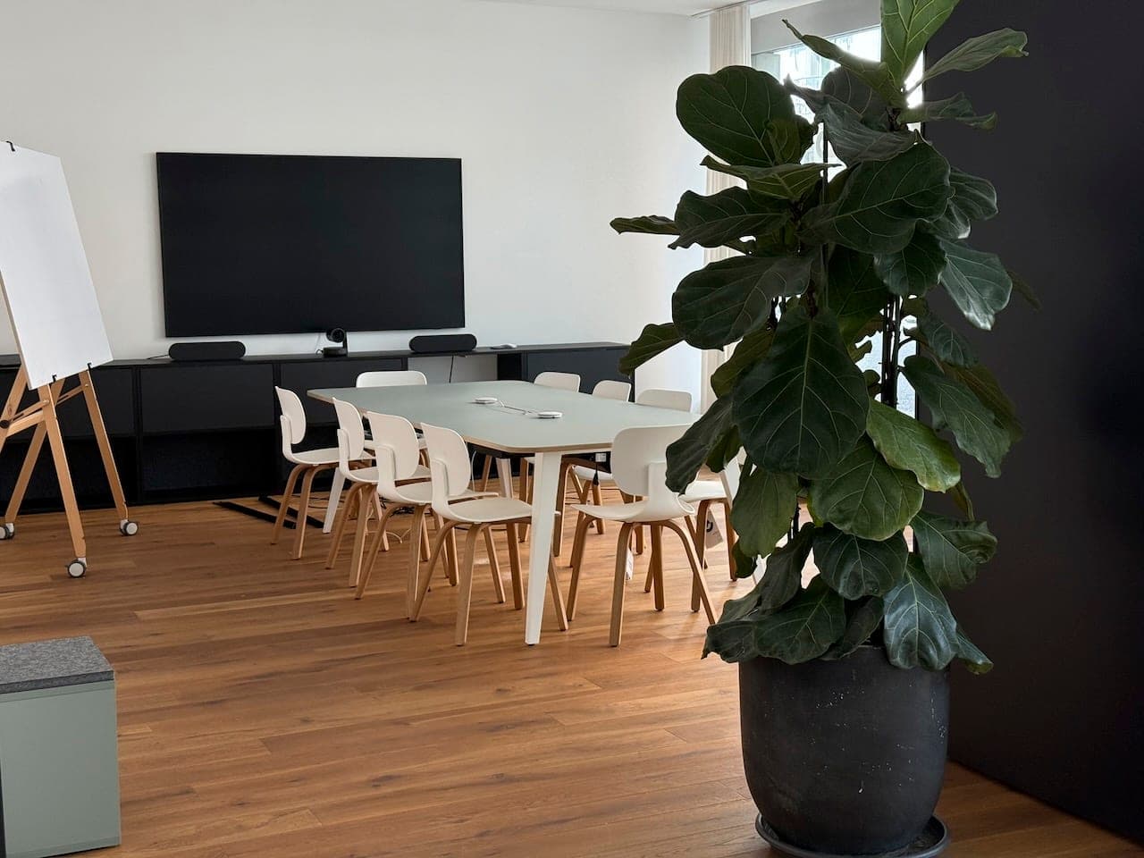 Zemp Meetup in Luzern: Sitzungstisch mit weissen Stühlen vor 85-Zoll-Screen mit Videokamera, daneben Flipchart